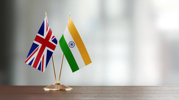 Indian And British Flag Pair On A Desk Over Defocused Background