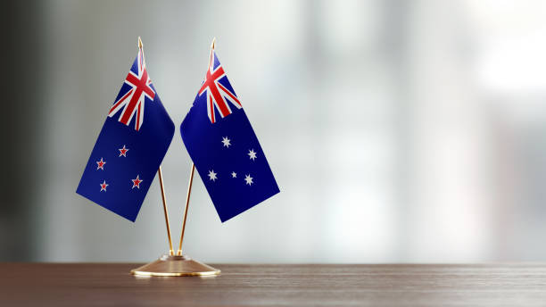 australian and new zealand flag paire sur un bureau sur fond défocalisé - new zealand flag photos photos et images de collection