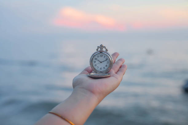istock pocket watch in hand on sea scape background. 915978486
