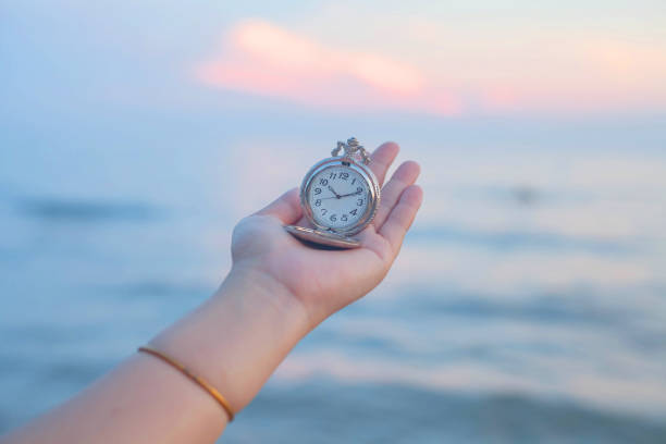 istock pocket watch in hand on sea scape background. 915978506