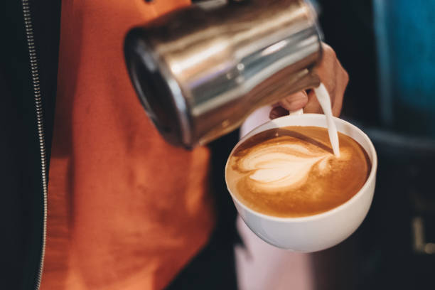 バリスタが心を作るコーヒー カップに牛乳を注いで - barista coffee coffee crop heart shape ストックフォトと画像