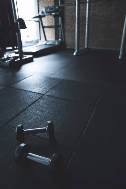 istock Dumbbells on empty floor in Gym background for workout 915981368