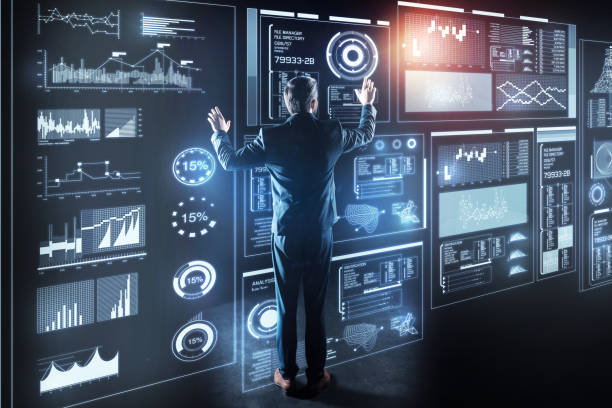 istock Elegant programmer standing in front of a giant transparent device and working 915991712
