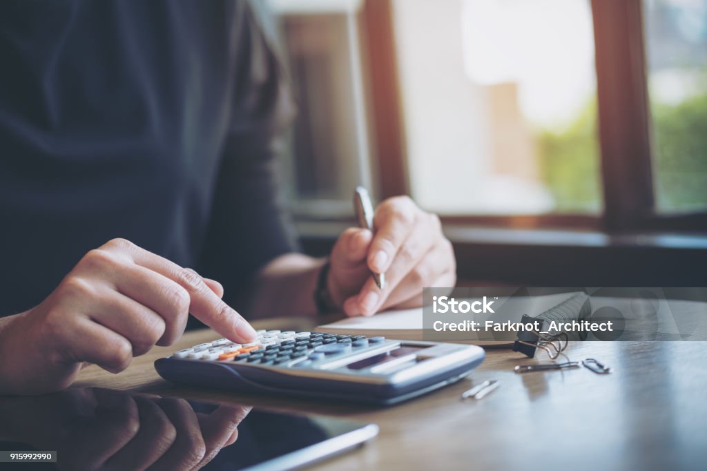 una mujer de negocios trabajando, usando calculadora y escribir en el cuaderno - Foto de stock de Calculadora libre de derechos
