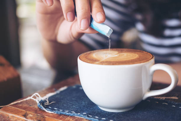 istock hand pouring white sugar in to white hot coffee cup 915993204