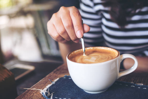 frau hält kaffeelöffel und heißen kaffee rühren - rühren stock-fotos und bilder