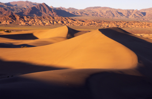 Strong wind shaping dry arid desert landscape scene with untouched majestic sand dunes and blue sky in Western Australia