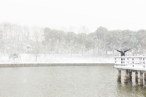young man relax in snow at a wooden bridge,personal perspective,China.