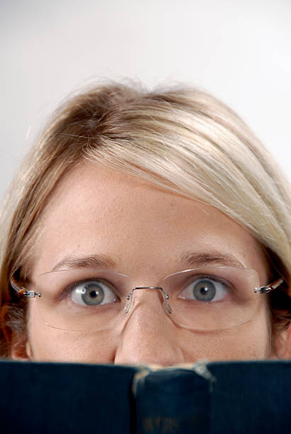 istock Pair of eyes, glasses peer above book. 91599983