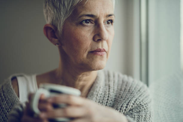 istock Thoughtful senior woman with tea cup looking through window. 916004732