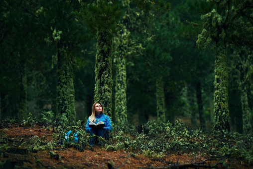 lifestyle shot of young woman in the woodland sitting and reading a book.relaxing concept.
