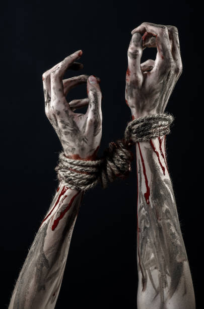 istock Hands bound,bloody hands, mud, rope, on a black background, isolated, kidnapping, zombie, demon 916011340