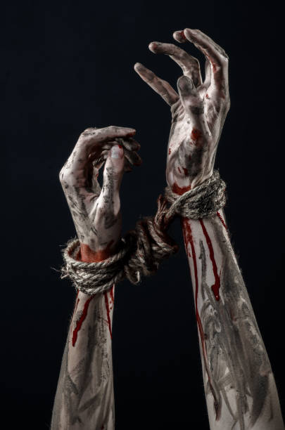 istock Hands bound,bloody hands, mud, rope, on a black background, isolated, kidnapping, zombie, demon 916011642