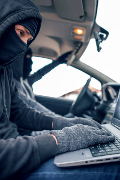 istock Car thief disarming car protections with laptop computer 916012800