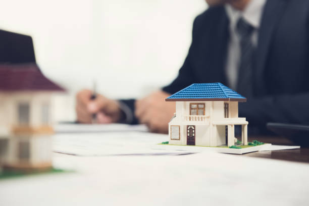 istock Real estate agent signing document with house model on the table 916016830