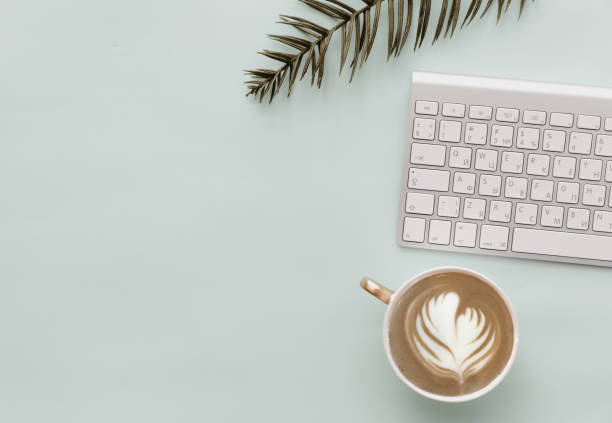 istock Minimalist Flat Lay Hipster Desktop With keyboard, coffee and green leaves 916021224