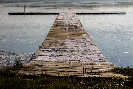 Fishing pier on a frozen lake. Bridge for mooring fishing boats and ice on the lake. Season winter.