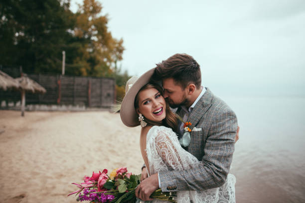 szczęśliwa narzeczeni w stylu boho obejmując na plaży - wedding beach bride groom zdjęcia i obrazy z banku zdjęć