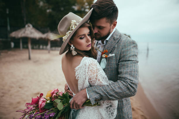 istock beautiful bride and groom in boho style hugging on beach 916025214