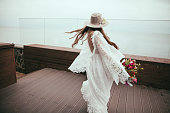 beautiful bride in bohemian wedding dress and hat with bouquet