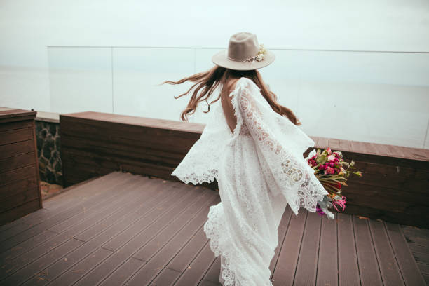 beautiful bride in bohemian wedding dress and hat with bouquet beautiful bride in bohemian wedding dress and hat with bouquet wedding fashion stock pictures, royalty-free photos & images