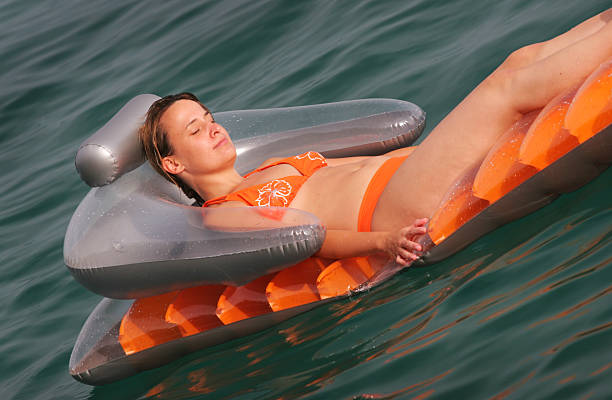 девушка на матрас в море - surface level water surface emotional stress water стоковые фото и изображения