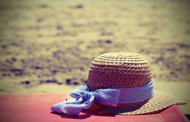 The  straw hat lies on the trunk of palm trees near the sea