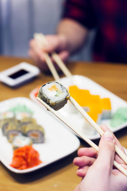 istock Sushi rolls on plate, friends taking rolls 916038772