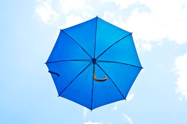 istock Blue umbrella flying on a blue sky 916043880