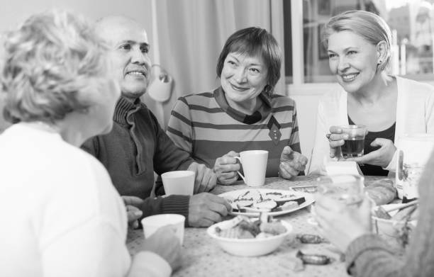 istock Smiling aged friends are sitting at table with tea and talking about life 916044662