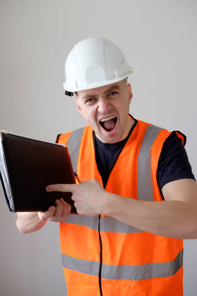 istock angry builder worker in orange protecting cask and working clothes pointing with finger 916048194