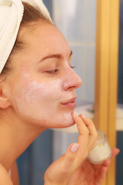 istock Woman applying mask cream on face in bathroom 916048356