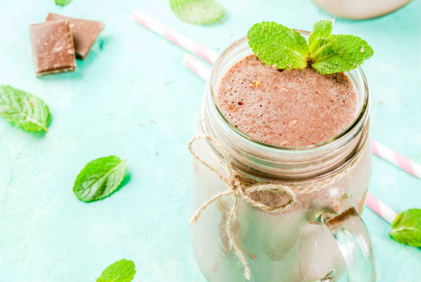 Chocolate smoothie or milkshake Chocolate smoothie or milkshake with mint and straw, in mason jar on light blue background, copy space close view low carb diet photos stock pictures, royalty-free photos & images