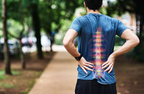 He's overdone it this time with his training Rear view shot of a sporty young man holding his back in pain while exercising outdoors spinous process stock pictures, royalty-free photos & images