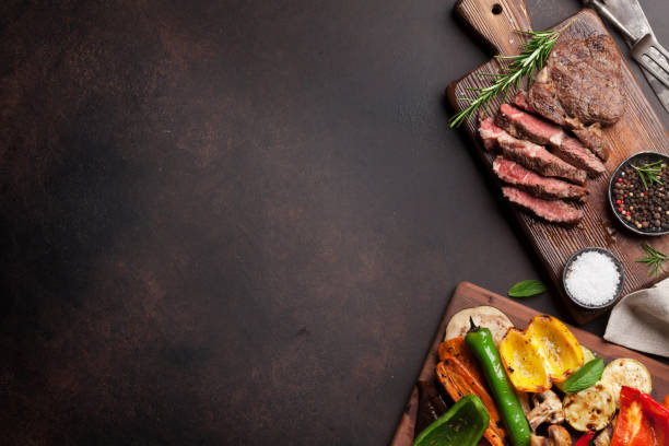 Grilled vegetables and beef steak Grilled vegetables and beef steak on cutting board on wooden table. Top view with copy space barbecue grill food stock pictures, royalty-free photos & images