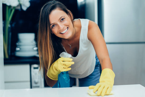 istock Positive young housewife using spray for cleaning 916065094