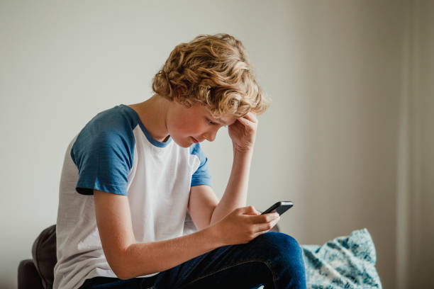 Teenage Boy uses Phone A teenage boy uses his phone to message his friends. one teenage boy only stock pictures, royalty-free photos & images