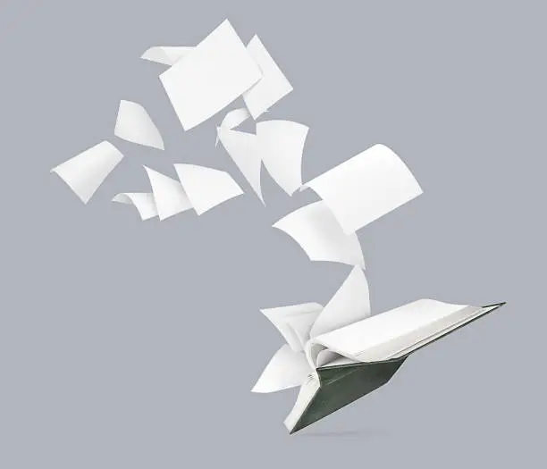 Photo of An empty book with flying pages isolated on a gray background