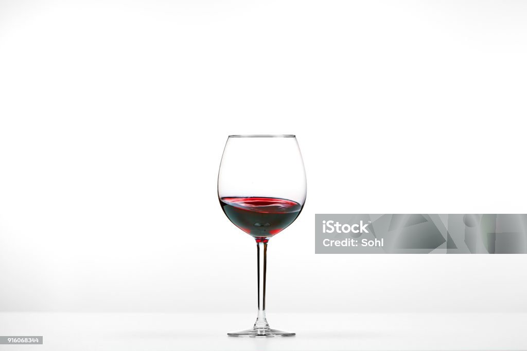 red wine glass on white backdrop Red wine glass with wine in the center of pictures. The wine moves slightly up the glass. Wineglass Stock Photo