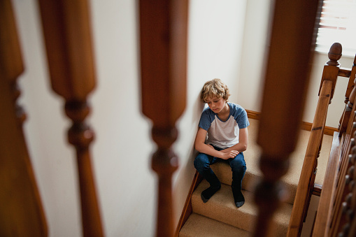 A teenage boy sits on the stairs alone.