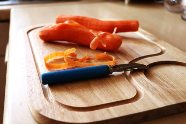 istock Two bigs carrot on wooden board with blue scraper 916068744