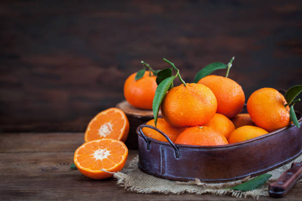 istock Fresh tangerines with leaves on  wooden table 916071854