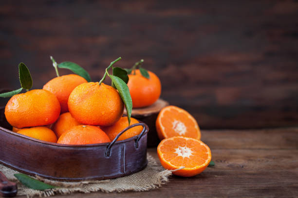 istock Fresh tangerines with leaves on  wooden table 916071860