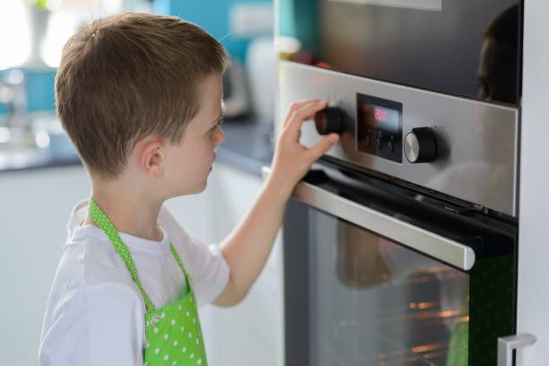 istock Child boy regulating temperature of the oven. 916072362