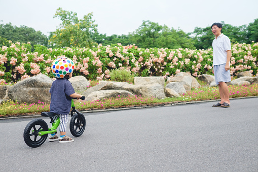Young father spend time with Cute little Asian 18 months / 1 year old toddler boy child, Dad and son play and have fun with balance bike (run bike), Dad tech son to ride bike, Selective focus at kid