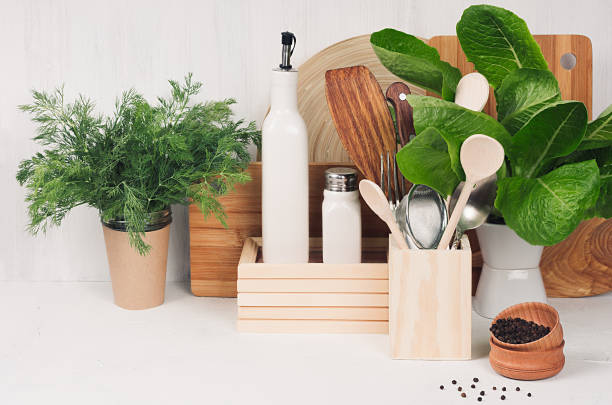 istock Kitchen white interior with wooden beige kitchenware, spices, ceramics and green spinach bush on light wood board, copy space. 916079948