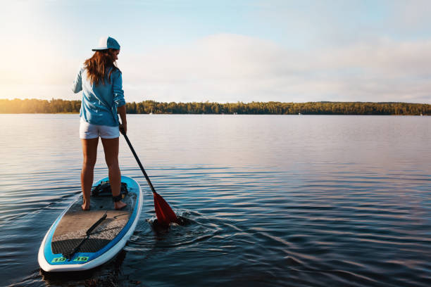 Out exploring the waters Shot of a young woman paddle boarding on a lake paddleboard stock pictures, royalty-free photos & images