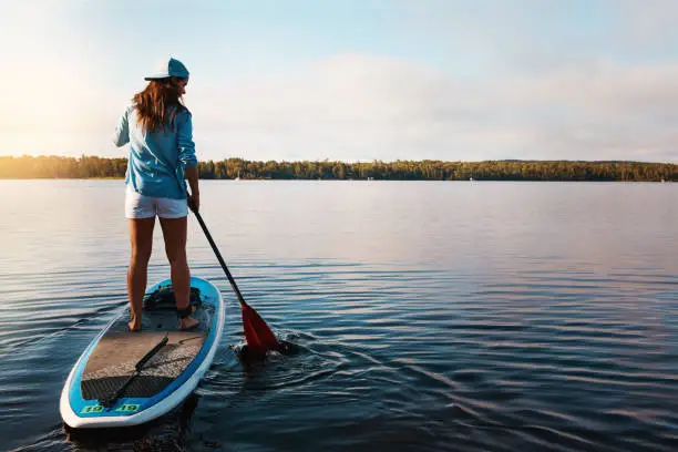Shot of a young woman paddle boarding on a lake