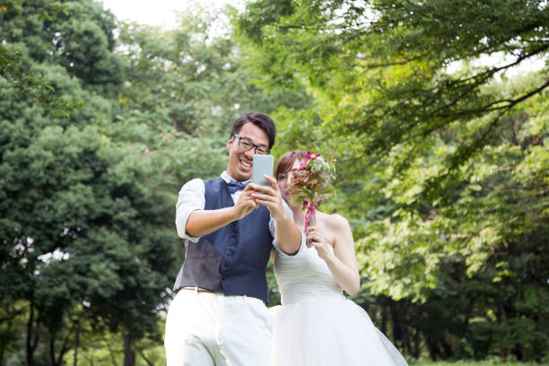 noiva e noivo, vestindo trajes de casamento tendo uma selfie no parque - welcome sign greeting congratulating wedding - fotografias e filmes do acervo