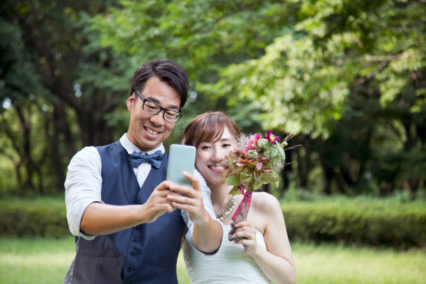 noiva e noivo, vestindo trajes de casamento tendo uma selfie no parque - welcome sign greeting congratulating wedding - fotografias e filmes do acervo